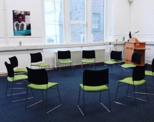 a white room with ten chairs placed in a circle ready for an improv class
