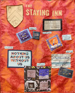 An orange and red flock wallpaper fabric with several embroidered patches on it. Top Left is a shield embroidery in beige with brown thread and to the right of that The Staying Inn is written in beige felt letters