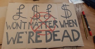writing without words at the scottish crannog centre a cardboard placard that reads £$£$ wont matter when we're dead