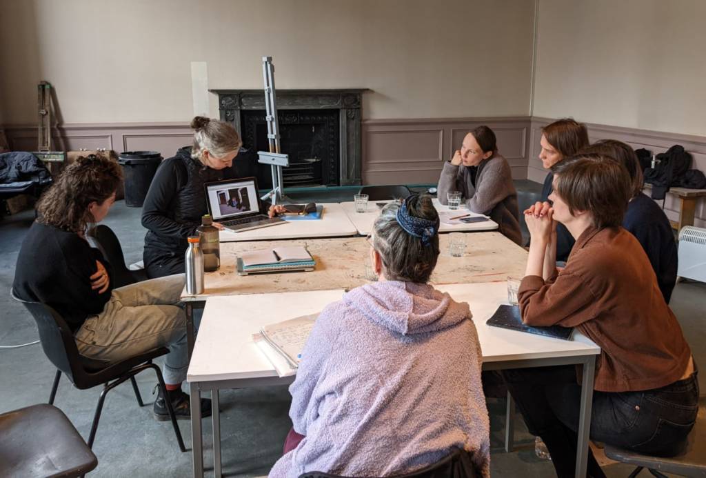 Artists sit around a large table in discussion in the Arbroath Courthouse studios.