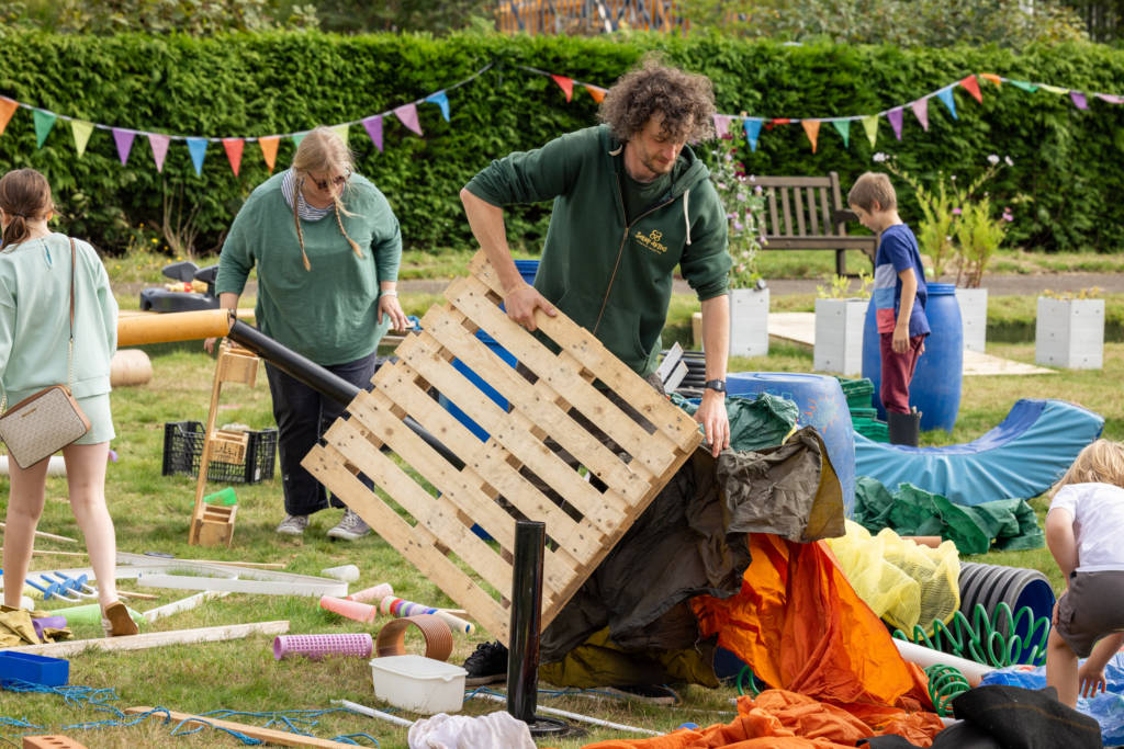 Photograph of ScrapAntics setting up the Loose Parts Play area with scrap material and wooden pallets