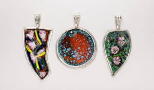 Photograph of three brightly coloured, enamel necklace pendants.