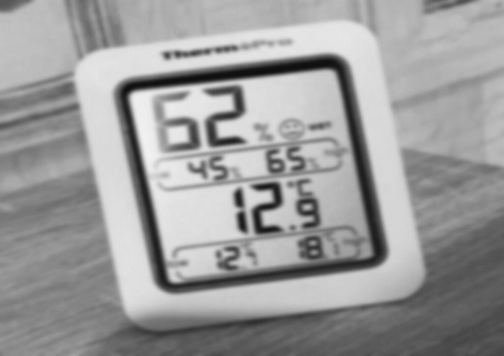 Black and white photograph of a smart energy metre showing the temperature at 12.9 degrees.