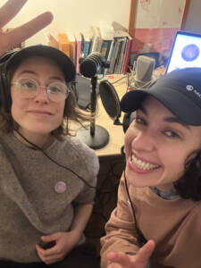 Becca and Su of dundee radio club pose for a selfie – each wears headphones and three mic sit on the table behind them.